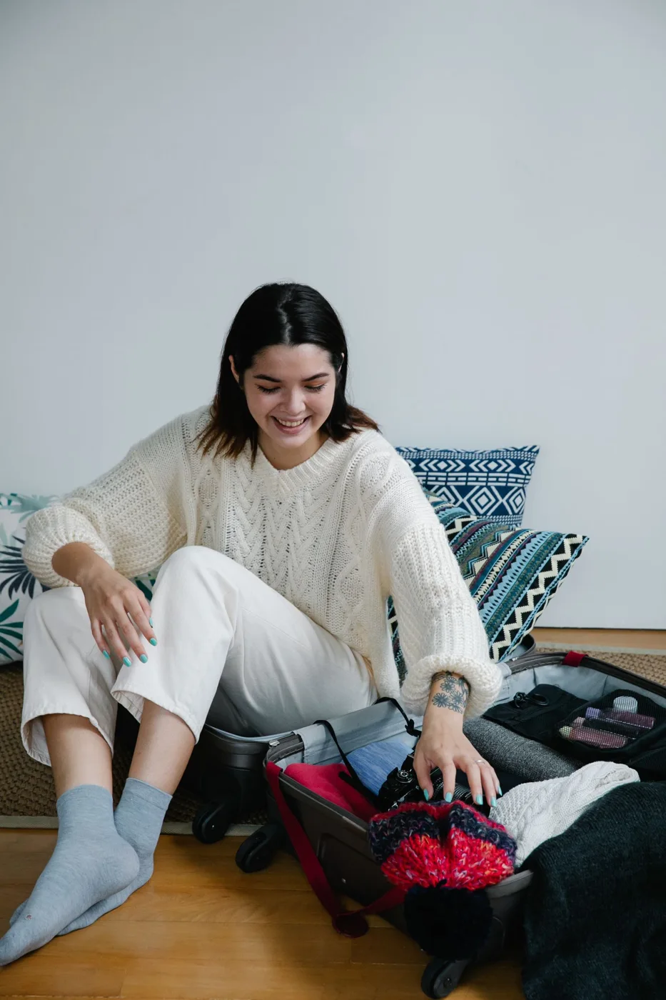 A woman sitting with an open suitcase while preparing to travel
